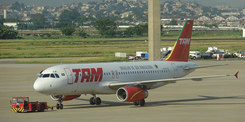 A TAM Airbus at the GIG airport, against the backdrop of the populous city