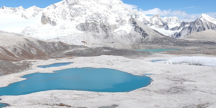Gangkar Phuensum lakes in sandy land and snow covered mountains all around them
