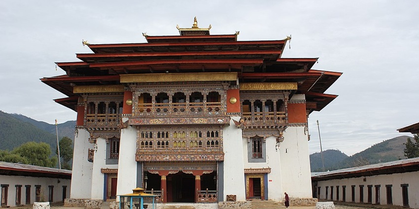 An image of the Gangteng Goenpa, with ornate woodwork, colorful details, and a mountainous backdrop