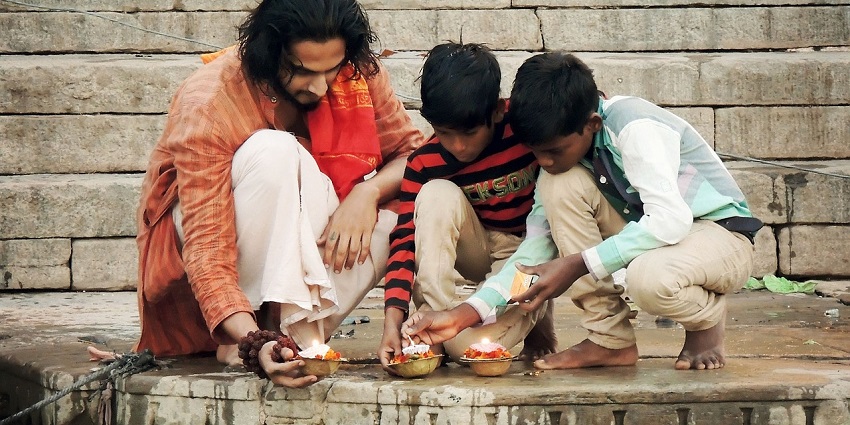 An image showing a man and boys in prayer, similar to rituals performed during Garia Puja.