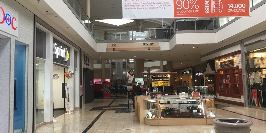 Interior view of a shopping mall with a cash counter in front and a Sprint store on the left