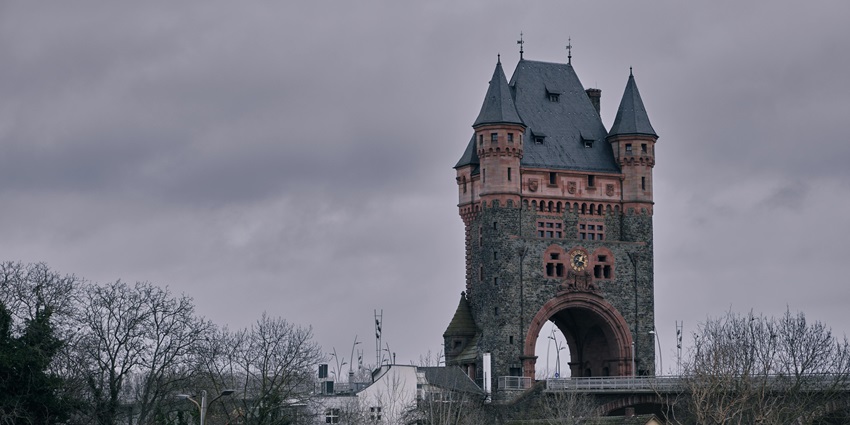 Worms’ historic Nibelungen Bridge Tower in Germany under an overcast, cloudy sky.