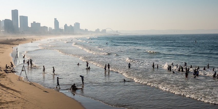 Kitesurfers and swimmers enjoying the peaceful shores of Durban Beach in South Africa.