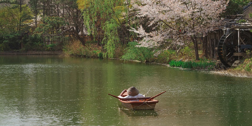An image of a man riding a boat on the smallest lake in the world