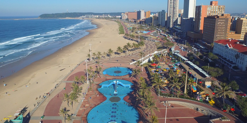 People enjoying a sunny day along the vibrant beachfront with tall city buildings