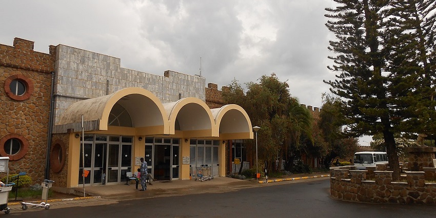 Gondar Airport with its name displayed on top, a road in front, and lush trees surrounding it