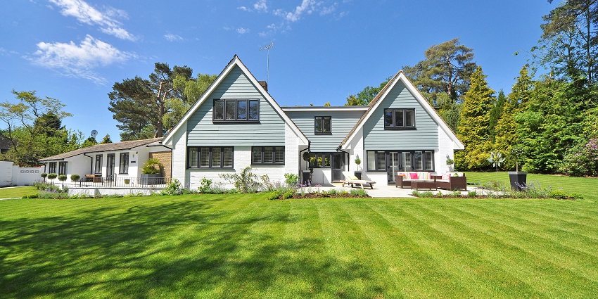 An image of a large Estate with white and blue exterior, surrounded by trees, similar to the Good Hope Estate in Falmouth.