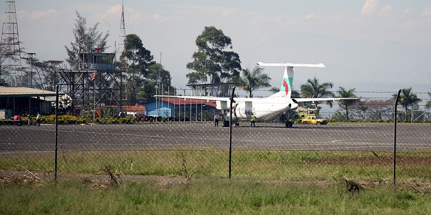 Goroka airport, one of the airports in Papua New Guinea, with steel net fences, a small aircraft parked on the runway and people standing nearby