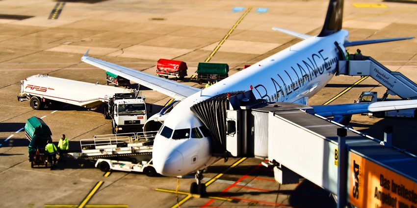 A passenger standing by the window is taking photos of an aircraft on the runway.