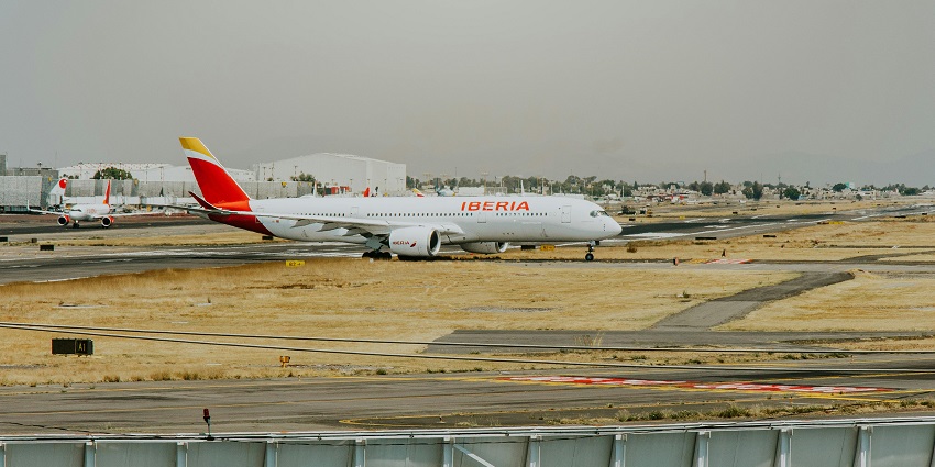 Airport with aeroplanes parked on the runway and large white warehouses in the back