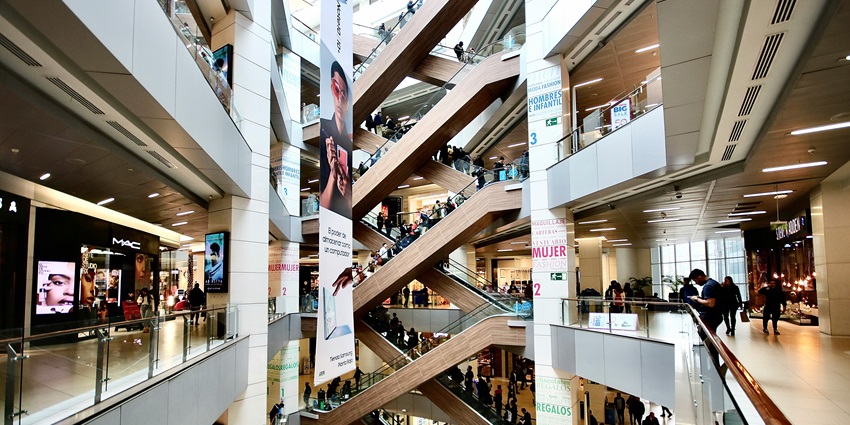 Image of people walking and shopping inside a large, bright mall with glass storefronts.