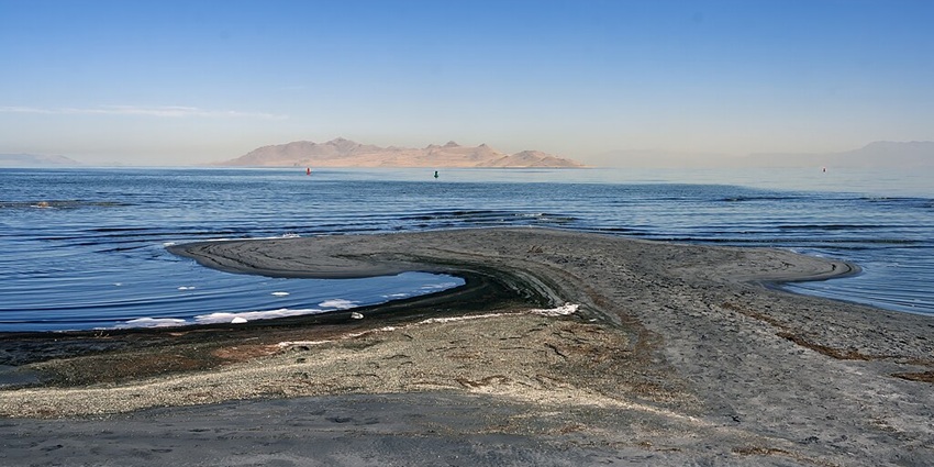 Image of the Great Salt Lake with sandy and rocky shoreline and sand mountains at distance