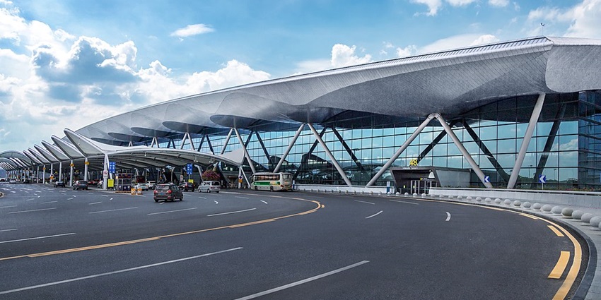 Guangzhou Baiyun Airport control tower with a clear sky and terminal buildings below