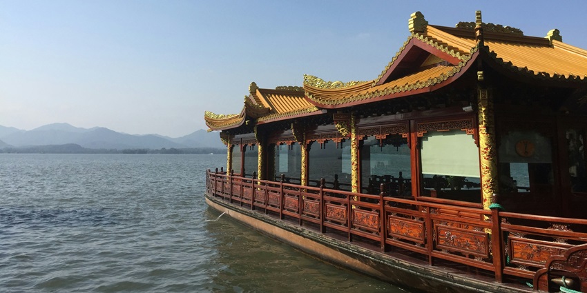 A traditional wooden house on stilts, surrounded by calm waters and lush greenery, reflecting the serene landscape