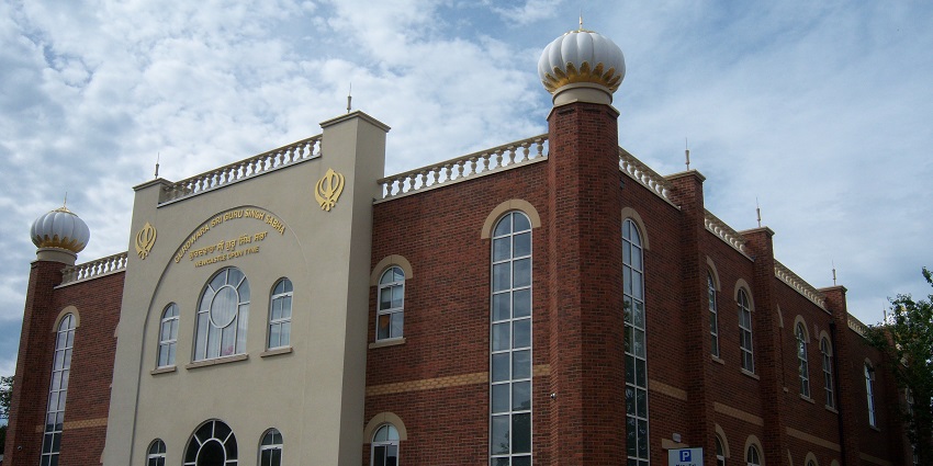 Exterior facade with brown walls and white dome of Gurdwara Shaheed Baba Deep Singh Ji.