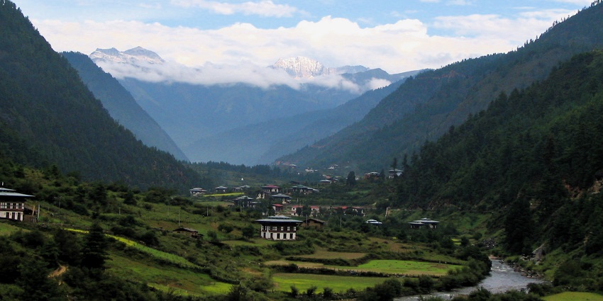 Scenic views of Haa Valley with lush green fields, traditional Bhutanese houses, and majestic mountains in the background.