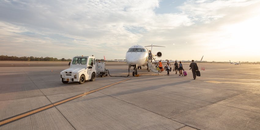 An aeroplane parked on the runway of one of the airports in Saudi Arabia with multiple passengers boarding and a vehicle