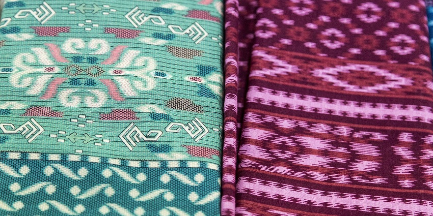 An image of vibrant handmade batik and ikat fabrics showcase a rich cultural heritage.