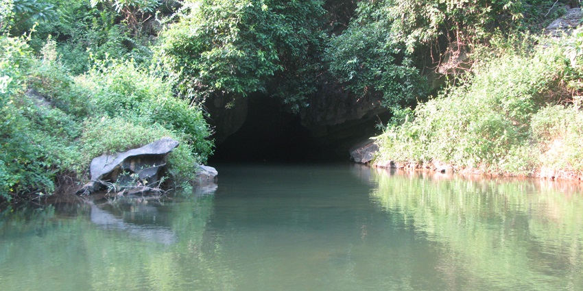 An image of Hang Nấu Rượu Cave in Tràng An, Vietnam, featuring a serene waterway and limestone formations.