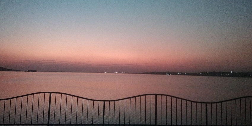 Lake with a silhouette of the boundary railings and a colourful sky during the evening