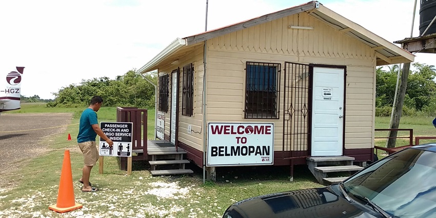 Hector Silva Airport with small hut, a man standing next to a board and an aeroplane