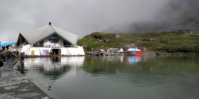 A beautiful Sikh temple set on the top of a mountain and is surrounded by dense greenery.