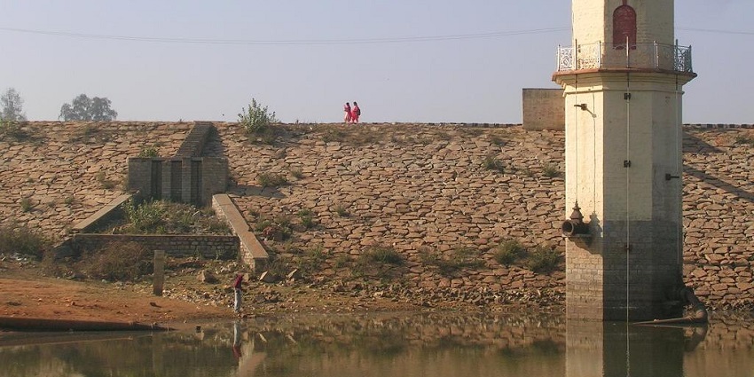 Hesaraghatta lake with some amount of water, grassy areas, and a pump house structure