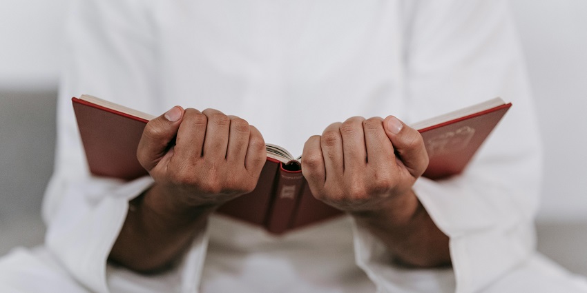 An image showing a person holding a Quran and praying on Islamic New Year, Hijra.