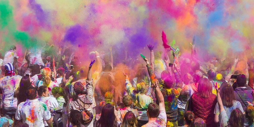 An image of people covered in a variety of vibrant colours celebrating the festival of Holi.