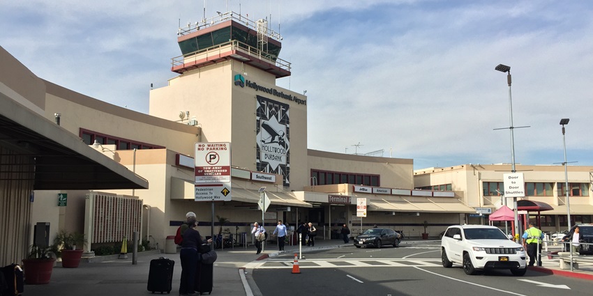 Terminal building of Hollywood Burbank with people carrying their luggage and vehicles.