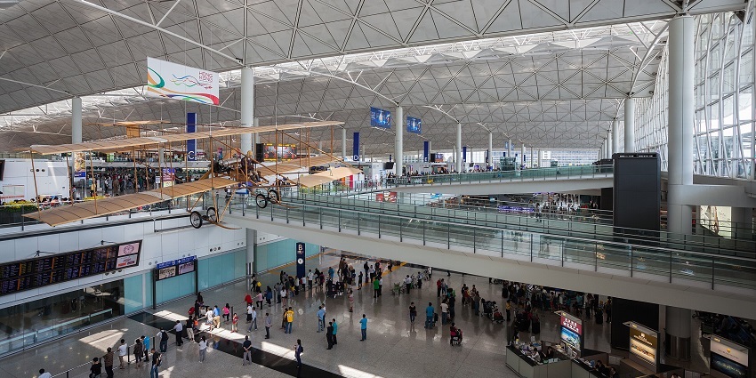 An image of Hong Kong International Airport in Asia, featuring a modern terminal with parked aircraft