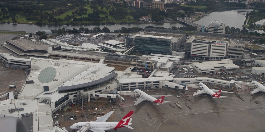 Sydney airport from above with multiple aeroplanes parked and the airport terminal buildings