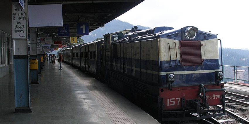 Platform of Shimla railway station with multiple signages, people walking on the platform