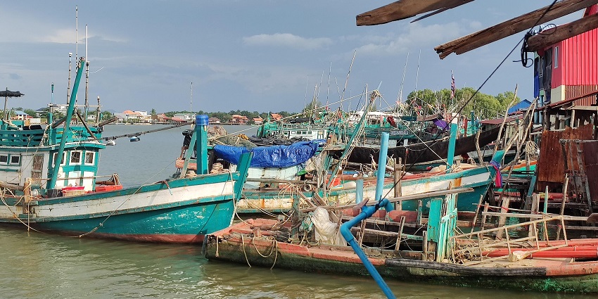 Image of a boat in Kampot, Cambodia, floating on the water with a distant shoreline