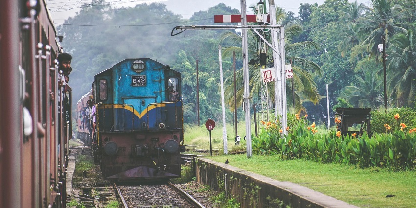 A vintage blue and brown train on railway tracks, captured in motion in a scenic backdrop