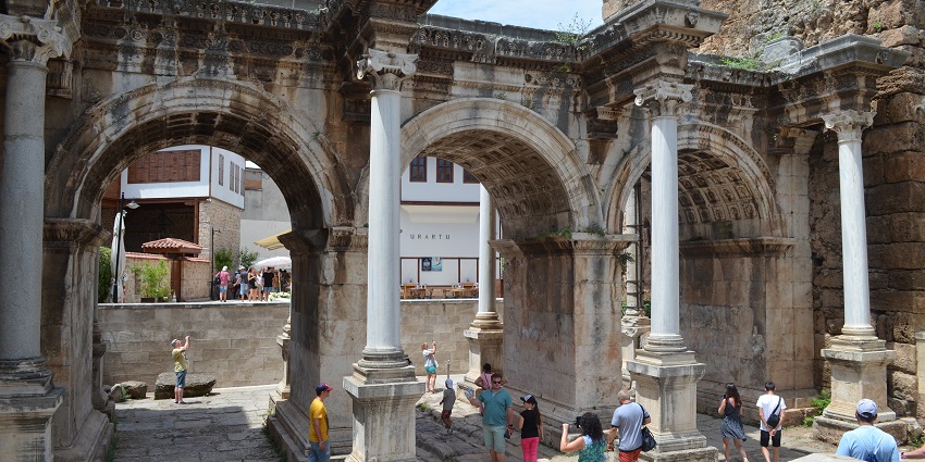 A picture of visitors walking toward Hadrian's Gate on a cobblestone street.