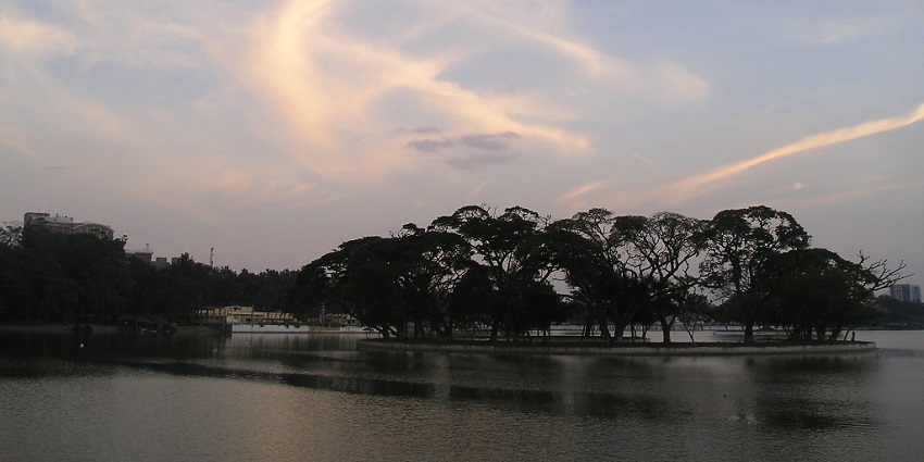 A tree-lined road to one of the biggest lakes in Bangalore, with a clear path for walking.