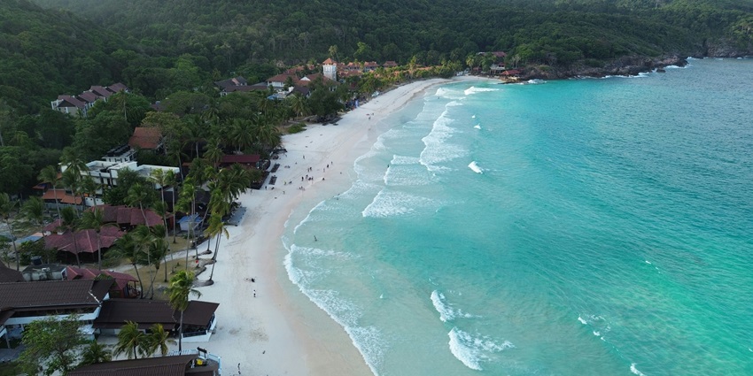 view of the golden shores of the island and turquoise waves crashing