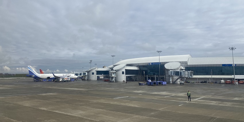 Srinagar international airport with an Indigo airplane parked, the airport building and a man