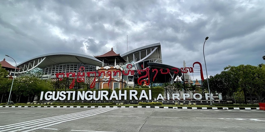 Ngurah Rai International Airport welcome sign with Balinese carvings and tropical plants