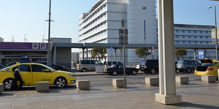 Vehicles and taxis are waiting outside the Athens International Airport terminal building.
