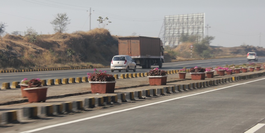 A wide-angle view of a highway in Maharashtra, India, with a road surrounded by greenery.