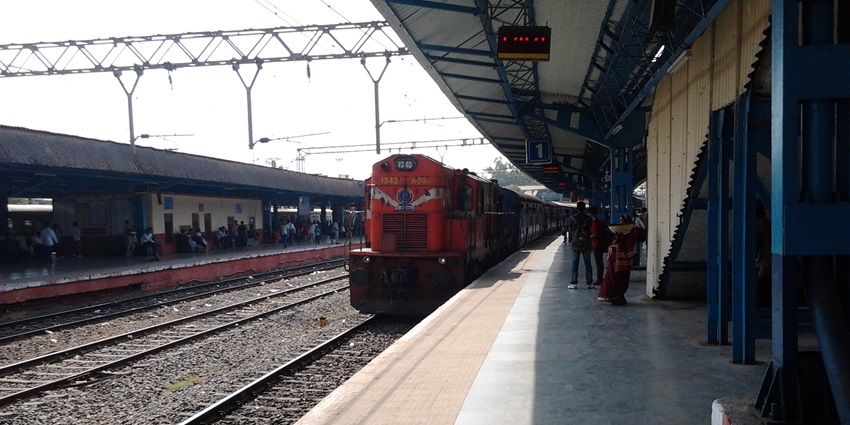 Lonavala railway station with a red train coming and people standing on the platform