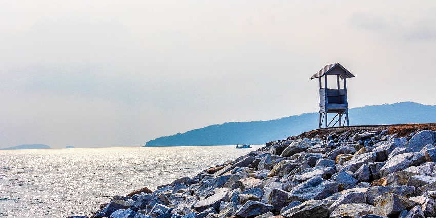 View of the rocky shores of Rayong city, with a lighthouse, with the clear blue sky in the background