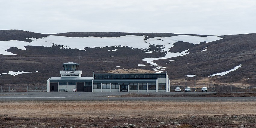 Húsavík Airport in Iceland is shown with a small terminal building and a beautiful mountain view.