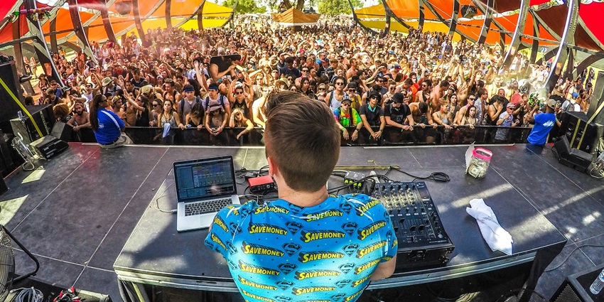 An image of a crowd vibing and enjoying to the beats of DJ in a music show