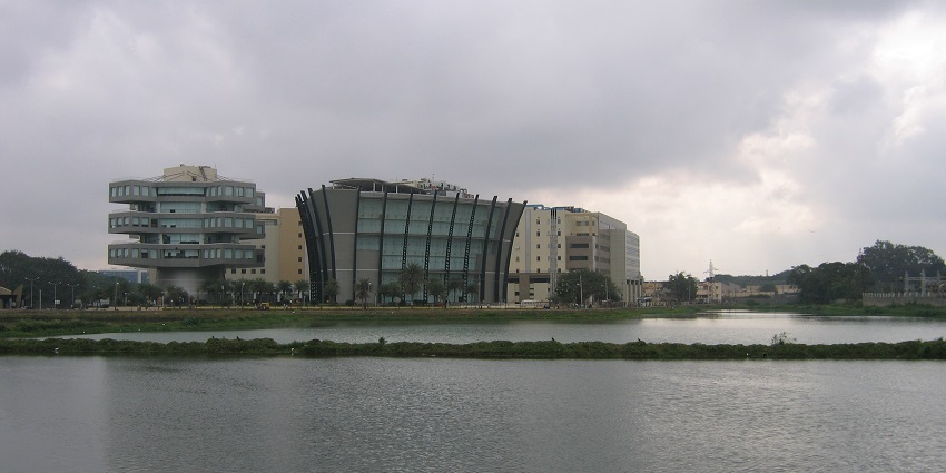 Lake in Whitefield with a green shore dividing the lake and modern architectural buildings.