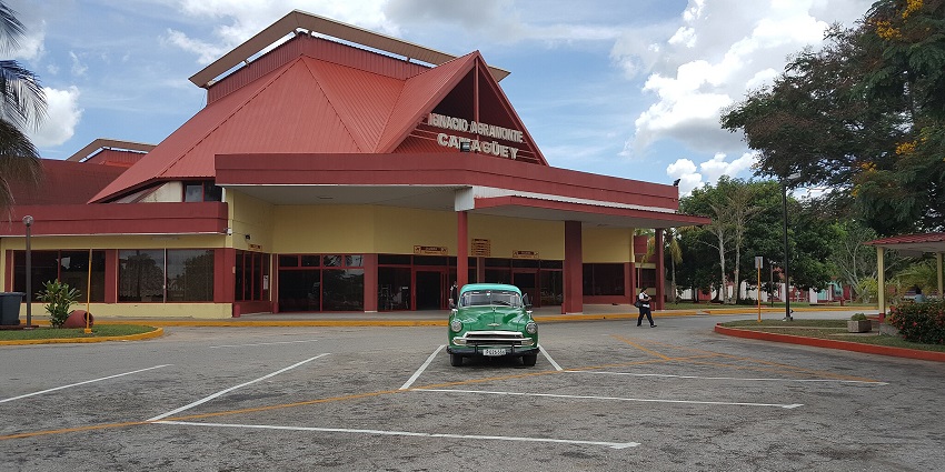 Ignacio Agramonte International Airport with red buildings and a green car parked
