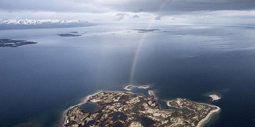 A view of the Iliamna Lake with an Island, with the reflection of rainbow formation