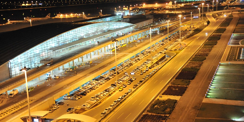 An expansive view of the IKIA airport terminal at night with aeroplanes lined up on the tarmac.